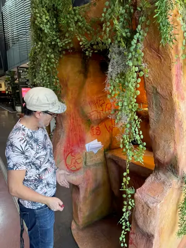 Marcelo Zavala-Baeza outside the installation entrance, a sculpted rock overhang draped with native plants